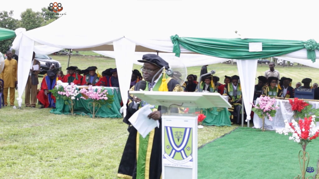A speaker addressing an audience at an outdoor academic ceremony
